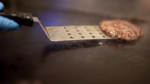 Closeup View of Roasting Beef Cutlet for Hamburger in Restaurant Chef Turning Meat on Kitchen Stove