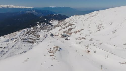 Vue panoramique lente prise par un drone du centre de ski de Parnassos, survolant les remontées mécaniques et les télécabines