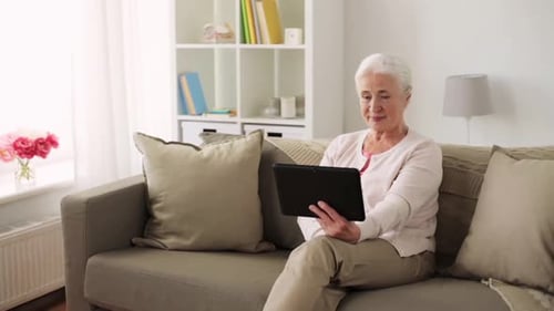 Senior Woman Relaxing on Couch Using Tablet