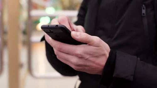 Handsome Young Man Using Smartphone in the City Amusement Park at the Evening