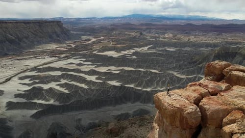 Drone Shot of Lonely Woman Standing on The Edge of Cliff Above Deep Canyon in Desert of Utah USA