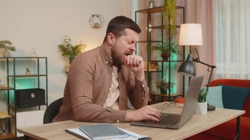 Bored Sleepy Young Businessman Freelancer with Laptop Sleeping at Home Office Desk in Living Room