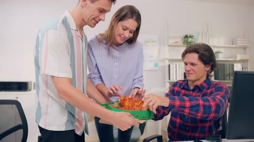 Group of businessman and woman eat pizza while working in the office.