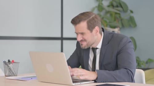Frustrated Businessman Typing on Laptop in Office