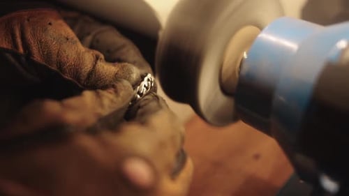 A Person Polishing a Piece of Jewelry with a Blue and White Polishing Machine