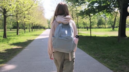Kleines Mädchen mit Rucksack, das nach dem Schulunterricht spazieren geht Rückansicht