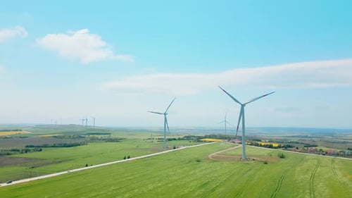 Wind Turbines Spinning in Green Field on Sunny Day