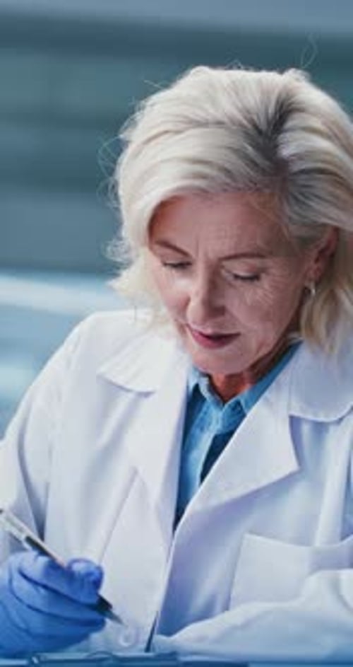 Woman in Lab Coat Taking Notes in Laboratory