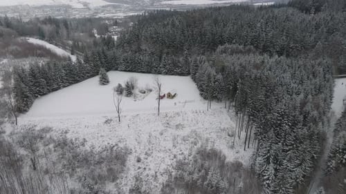 House in the wilderness of snow-covered forests. Winter in solitude from a drone view