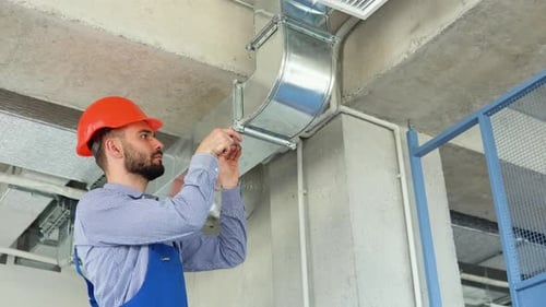Construction Worker Installing Ductwork in Commercial Building
