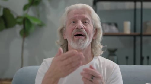 Senior Man Waving at the Camera While Talking