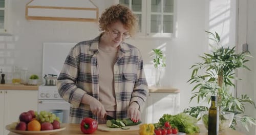Woman Cutting Cucumber in Bright Kitchen