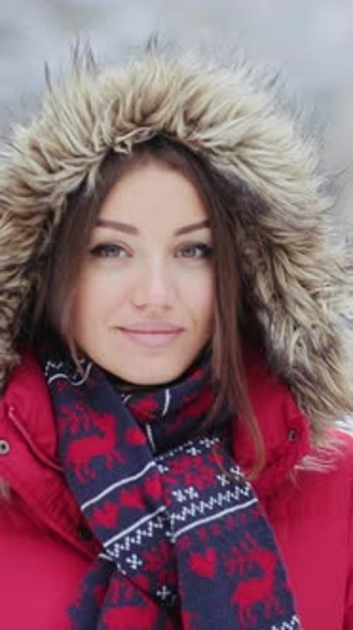 A Cheerful Woman in a Red Jacket Smiles Warmly in a Snowy Scene