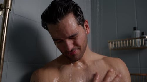 Muscular Man Showering in Tiled Bathroom