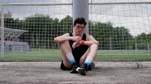 a Guy in a Sports Uniform and Glasses is Sitting and Looking at the Clock Smooth Camera Movement