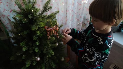 Child Decorating a Christmas Tree at Home