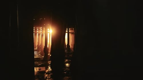 The sun's rays shining through the wooden beams in the ocean at Santa Monica Pier, California.