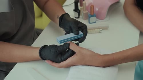 Anonymous Specialist Doing Manicure to Client Using File on Nails