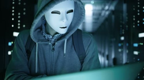Close-up of a Masked Hacker in Data Server Hacking Into System.