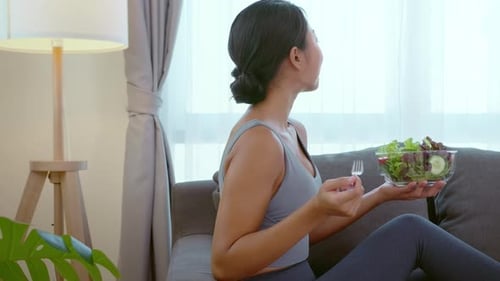 Woman Eats Healthy Salad at Home on Sofa