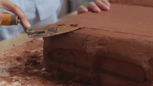 Close Up Of Woman Designer's Hands Using Spatula To Smooth Out Car Clay