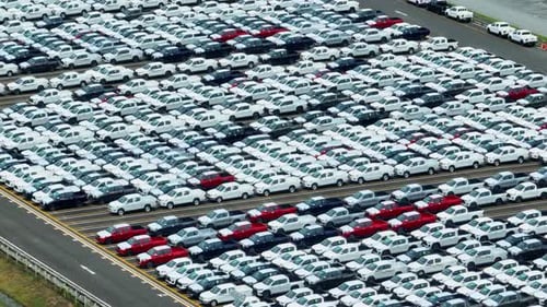 An aerial drone view reveals a sea of cars parked.