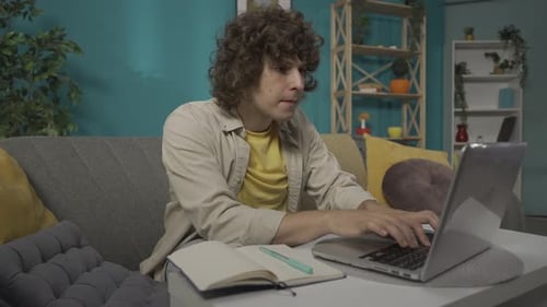 Young Adult Using Laptop and Notebook at Home