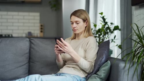 Woman Relaxing on Couch with Smartphone