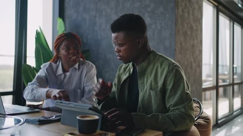 At a Cafe a Male and Female African American Business Duo are Using Hand Gestures While Pointing at