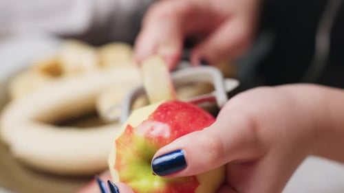 Woman peeling a ripe apple with peeler tool