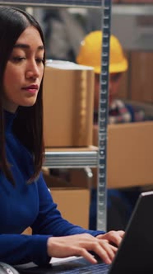Woman Uses Laptop Computer in Warehouse Setting