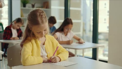 Children Write at Desks in Classroom