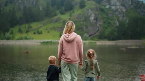 Woman Holds Children Hands Looking at Calm River at Highland