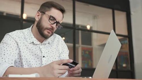 Man Using Online Banking with Laptop and Card