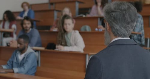 College Teacher Explaining New Information Speaking and Gesturing Looking at Students in Classroom