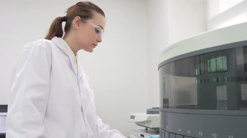 Female Lab Technician Operating Medical Analysis Machine