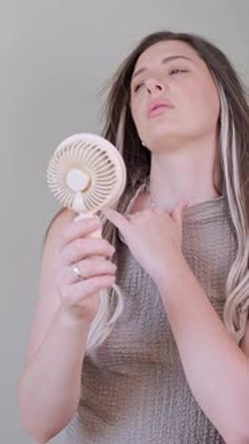 Woman Cooling Off with a Portable Fan Indoors