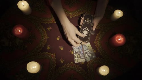 Vue du dessus : mains de femme cueillant une carte dans un jeu de cartes et faisant un plan de tarot divinatoire sur le