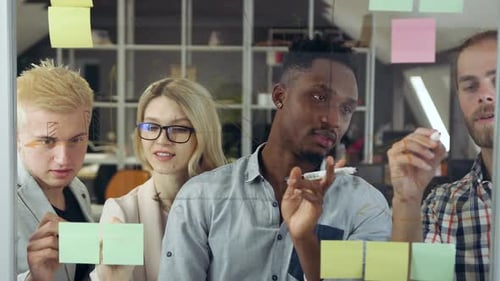 Creative Team Brainstorming Ideas on Glass Wall