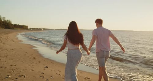 Young Loving Couple Have Fun Running on the Beach at Sunset