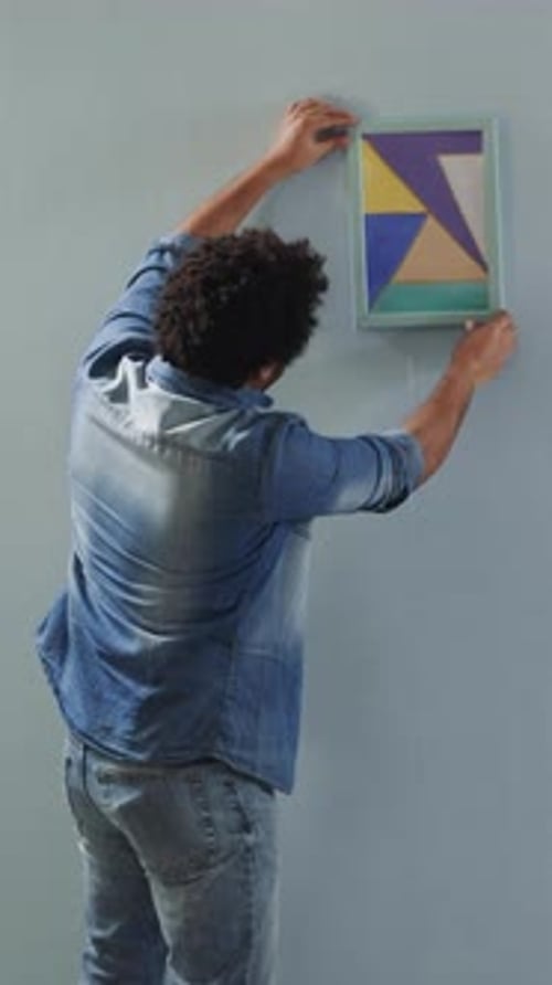 Black Man Chooses Place to Hang Picture on Wall with Friend