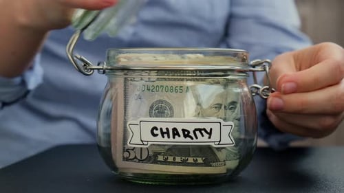 Putting Money in Charity Jar Close Up