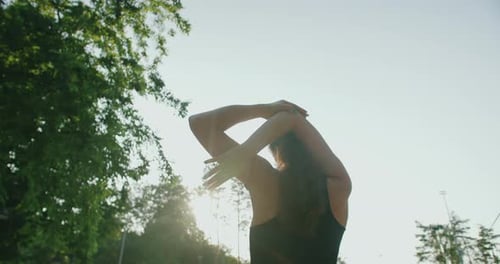 Woman Stretching Arms Overhead in Park