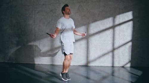 Strong Man Doing Cardio Workout with Jump Rope at Loft Room Sportsman Jumping