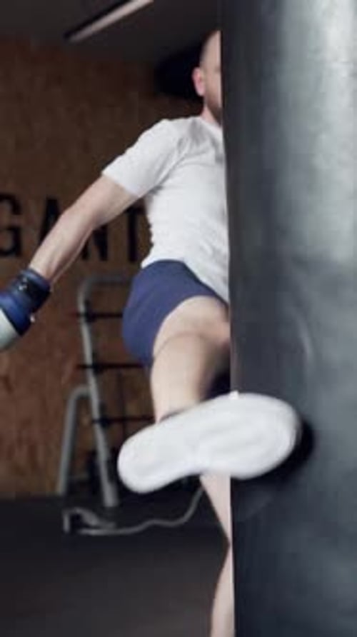 Man Kicking Punching Bag in Gym
