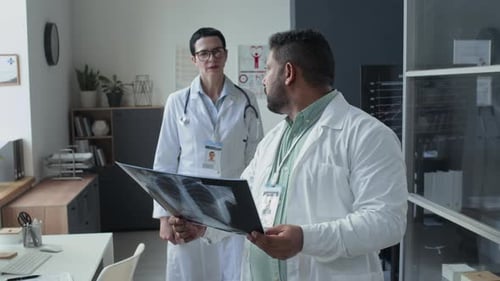 Doctor Discussing Chest-X-Ray with Female Colleague in Medical Office