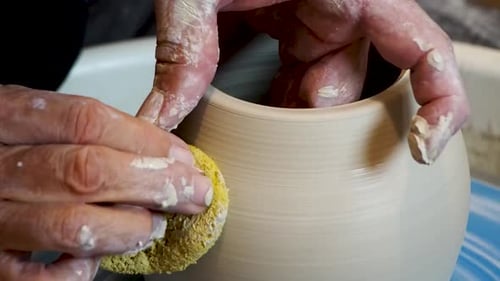 Close up of the potter's hand shaping and molding clay on a turning wheel .