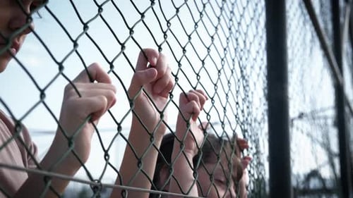 Sad Children Holding Chain Link Fence