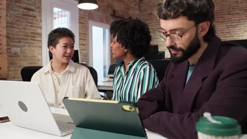 Team Discussing Technology at Desk in Modern Office