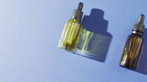 Close up of dropper serum bottles on blue background with copy space